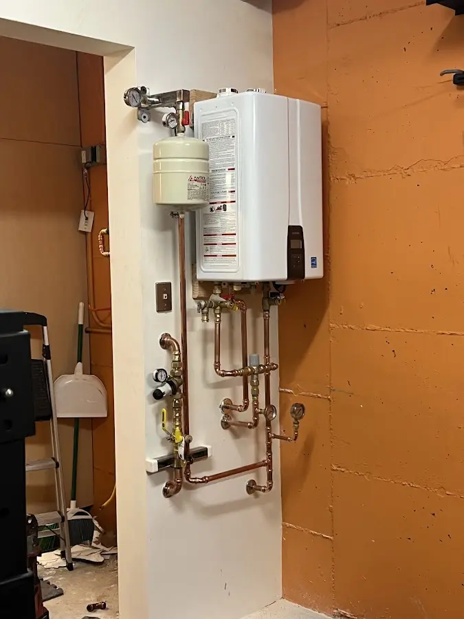 Plumbing technician inspecting water heater connections in Bullskin